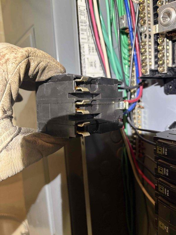 Troubleshot a recurring breaker trip on the AC circuit by inspecting the commercial distribution panel and measuring circuit current with a clamp meter, which read 1.7 amps AC under the load tested. Upon removing the breakers, found discoloration and sooty residue on the breaker stab clips and housings, indicating heat-related deterioration at the connection points. Documented the condition of the panel components and breaker connections as the likely cause of the intermittent tripping.