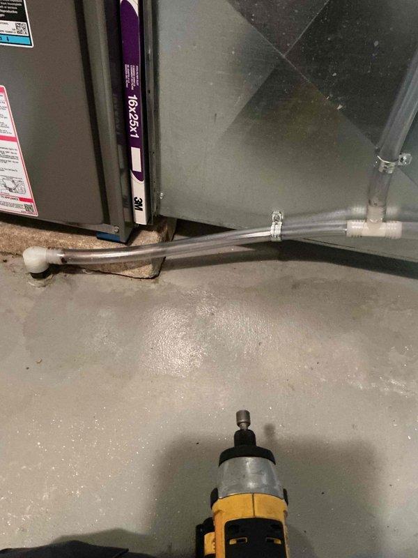 Returned to the site and cleaned the condensate drain lines, removing the heavy biological buildup and residue from the clear drain tubing that had restricted flow. Serviced the humidifier and reassembled the drain connections, verifying that the PVC fittings, tee, and clamp were secure and the drain assembly was free of blockage.