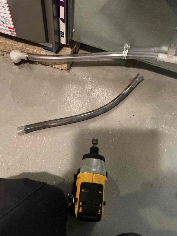 Returned to the site and cleaned the condensate drain lines, removing the heavy biological buildup and residue from the clear drain tubing that had restricted flow. Serviced the humidifier and reassembled the drain connections, verifying that the PVC fittings, tee, and clamp were secure and the drain assembly was free of blockage.