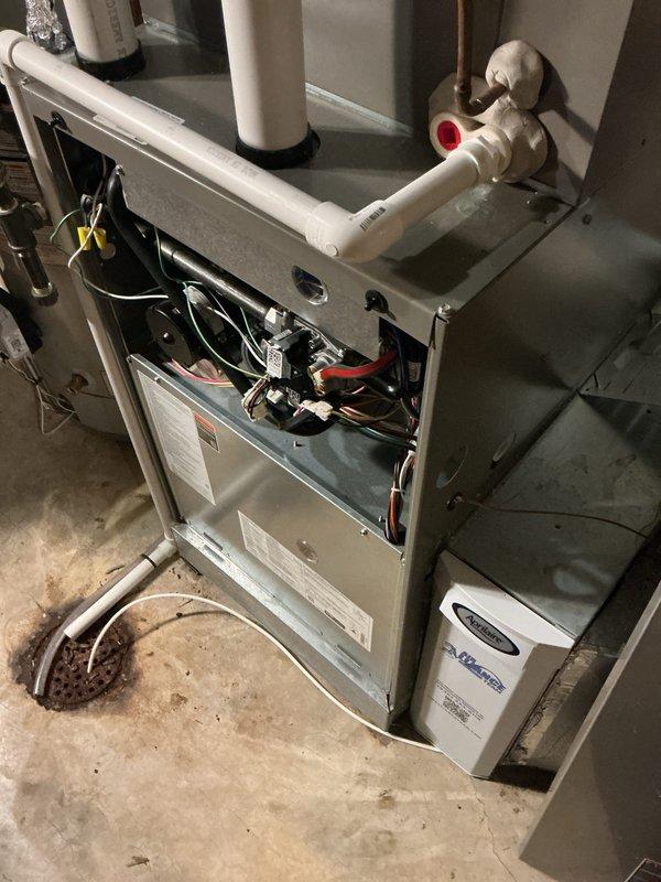 Performed a heating tune-up on a gas furnace, removing the front access panel to inspect the control board, relays, wiring harness, venting, and PVC condensate/vent piping for proper connections and condition. Verified thermostat operation and system response, and checked the filter condition and the adjacent humidifier installation. Reinstalled the access panel and confirmed the system was left in working order.