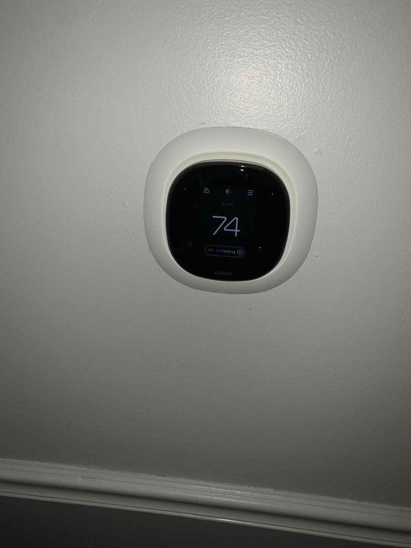 Performed a heating tune-up on a 2010-model single-unit system, verifying thermostat operation (set and holding at 74°F) and checking ambient humidity and temperature readings near the unit with a digital hygrometer. Inspected the surrounding area and noted heavy rust staining and corrosion on the adjacent surface, which may indicate moisture exposure and should be monitored.