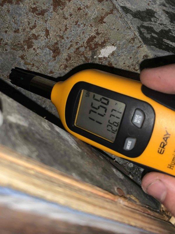 Performed a heating tune-up on a 2010-model single-unit system, verifying thermostat operation (set and holding at 74°F) and checking ambient humidity and temperature readings near the unit with a digital hygrometer. Inspected the surrounding area and noted heavy rust staining and corrosion on the adjacent surface, which may indicate moisture exposure and should be monitored.