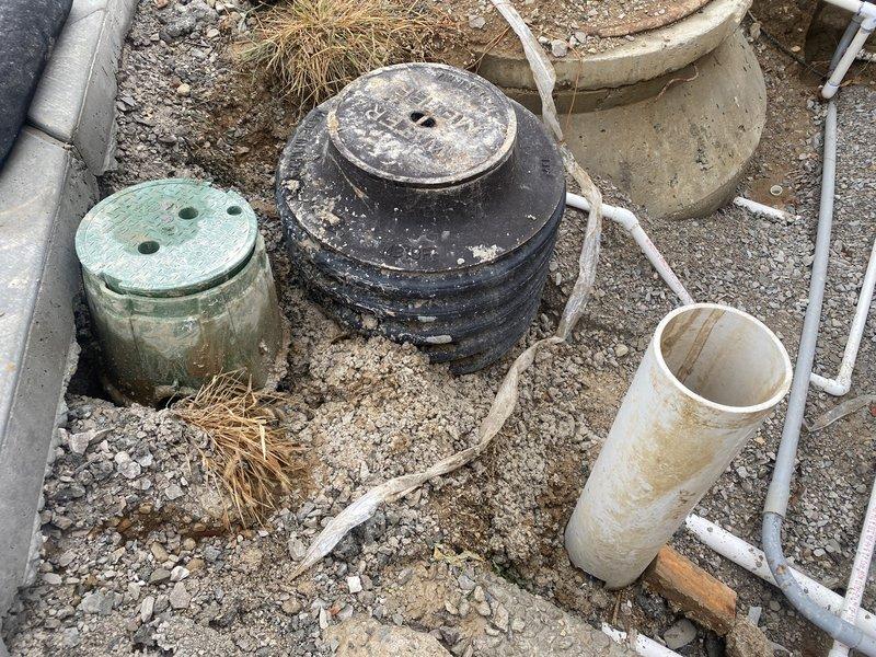 Performed a water test on the fountain supply system, inspecting the exposed valve box, riser, and PVC supply and conduit lines at the excavated site to verify proper operation. Confirmed fittings and piping were intact and the system was ready for continued fountain installation.