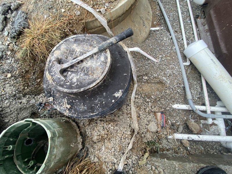 Performed a water test on the fountain supply system, inspecting the exposed valve box, riser, and PVC supply and conduit lines at the excavated site to verify proper operation. Confirmed fittings and piping were intact and the system was ready for continued fountain installation.