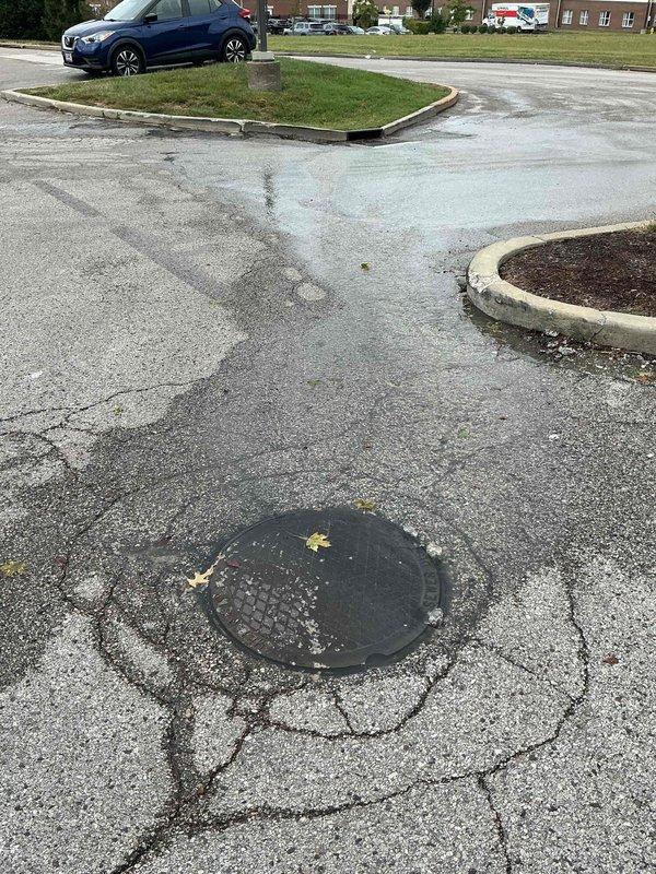 Responded to a reported sewer vent pipe backup and inspected the exterior sewer cleanout and surrounding drain line, where wastewater was surfacing and running across the pavement. Evaluated the main sewer line for blockage and restricted flow, with the cracked, deteriorated pavement around the access cover noted as a possible contributing factor. Documented site conditions with photos for follow-up recommendations.