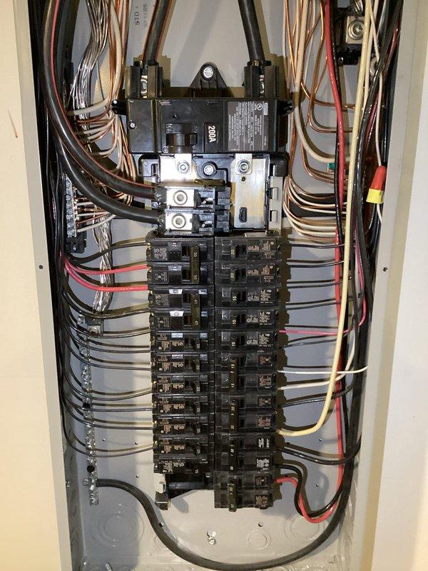 Following up on an HVAC request to verify breaker sizing, inspected the 200A main service panel and found the enclosure dry and undamaged, with orderly conductor terminations and no signs of burning, corrosion, or physical damage. Measured the HVAC unit's operating load with a Fluke 374 FC TRMS clamp meter, recording 45.2 amps AC, to evaluate whether the existing breaker is appropriately sized for the equipment's demand.