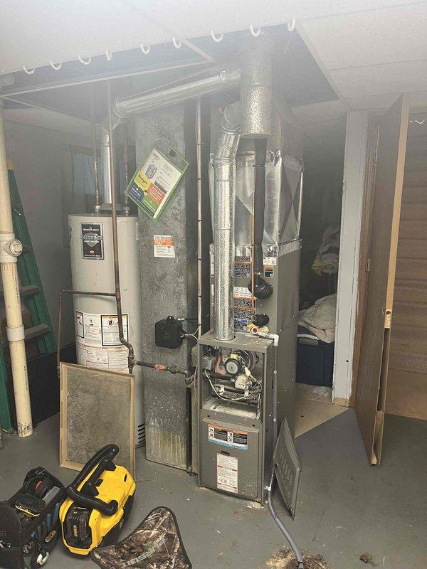 Performed a seasonal tune-up on a 5-year-old vertical gas furnace, removing the front access panel to inspect the burner assembly, gas valve, and control compartment. Found the return air filter heavily clogged with debris, which restricts airflow and reduces heating efficiency. Verified the Lennox smart thermostat was operating properly in heat mode with the humidifier engaged, and cleaned up the work area with a cordless vacuum upon completion.