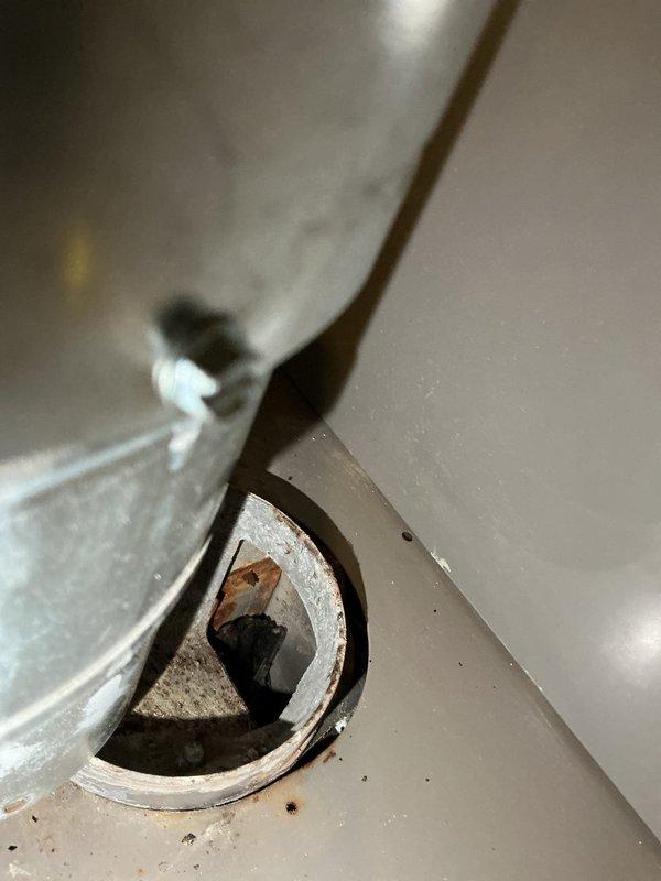 Diagnosed a Lennox furnace no-heat condition with a recurring E223 fault code (pressure switch/draft-related lockout). Inspected the flue collar and vent connection and found heavy corrosion and rust pitting at the collar, with sooty debris and a deteriorated baffle bracket inside the opening, indicating restricted or compromised venting. Removed and inspected the flame sensor/ignition probe, cleaned and serviced the components, and reassembled the unit for further testing, with the corroded flue collar recommended for repair or replacement to restore safe, proper draft.
