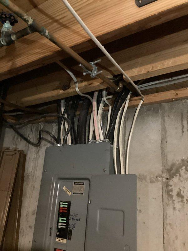 Evaluated the existing Sylvania service panel in the basement to determine upgrade requirements for an upcoming kitchen remodel and new appliance loads. Inspected the panel and found an older unit with handwritten circuit labeling and a dense, loosely routed bundle of branch cables entering the top through multiple connectors, indicating the panel is dated and likely lacks capacity for additional circuits. Recommended replacing the panel with a code-compliant unit to support the new appliances and meet current electrical code requirements, and prepared the scope of work for the estimate.