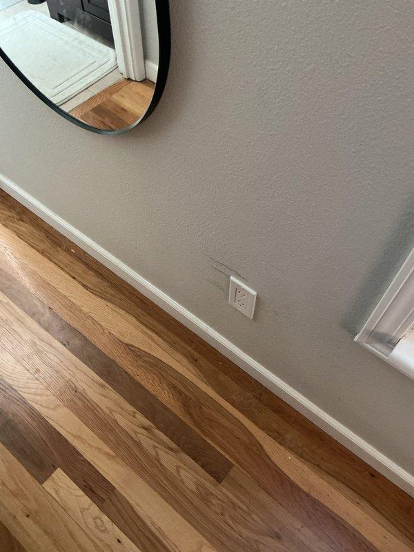 Performed troubleshooting of a wall-mounted television installation, inspecting the outlet and concealed wiring path behind the wall to diagnose the reported issue. Evaluated the receptacle and connected cord at the baseboard outlet and checked adjacent wall surfaces for signs of damage or interference. Documented existing conditions with photos.