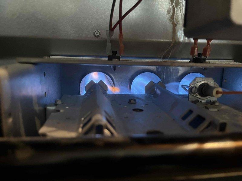 Performed a complete tune-up on the gas furnace, inspecting the burner assembly, flame sensor, igniter, and associated wiring connections. Verified proper ignition and stable blue burner flames across all heat exchanger ports, with a minor orange flicker noted on one burner that warrants monitoring. Tested thermostat operation and confirmed the system responds correctly to heat call, with the unit operating normally at completion.