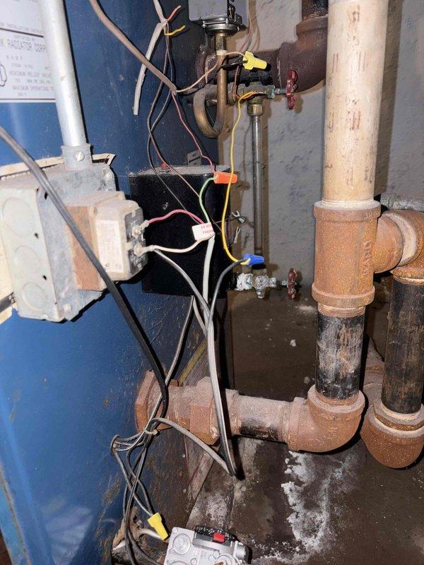 Responded to a no-heat call on an approximately 30-year-old Kenmore boiler and removed the lower access panel to inspect the burner tubes, combustion chamber, and control wiring. Diagnosis found significant corrosion at the piping fittings, standing water and residue pooled at the base of the unit, and deteriorated, tangled control wiring. The system's age and condition were documented with photos, and an estimate for repair or replacement will be provided.