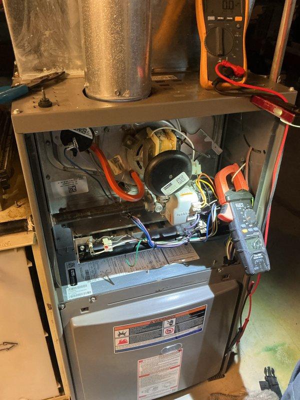 Responded to a no-heat call with no blower operation on a 15-year-old gas furnace and removed the access panel to perform electrical diagnostics on the control circuit, draft inducer assembly, and low-voltage wiring using a multimeter and clamp meter. Verified the thermostat display was blank, indicating a loss of low-voltage power to the control system, and traced the circuit to isolate the cause of the lack of heating and airflow demand.