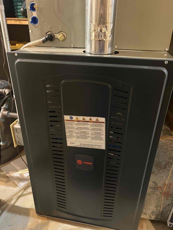 Performed a seasonal tune-up on a Trane gas furnace, including inspection of the cabinet, flue venting, and control board operation. Took electrical measurements with a clamp meter to verify proper component amperage draw and confirm the unit was operating within normal parameters, with no signs of rust, frost, or visible damage noted.