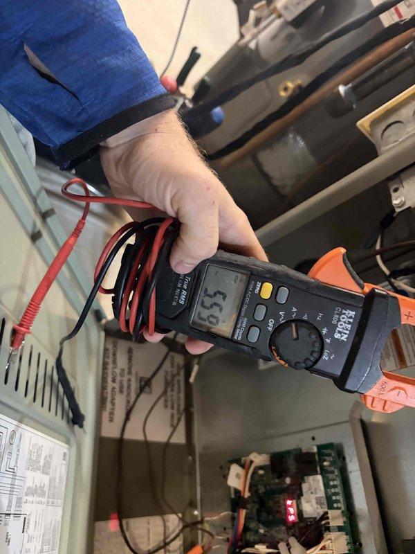 Performed a seasonal tune-up on a Trane gas furnace, including inspection of the cabinet, flue venting, and control board operation. Took electrical measurements with a clamp meter to verify proper component amperage draw and confirm the unit was operating within normal parameters, with no signs of rust, frost, or visible damage noted.