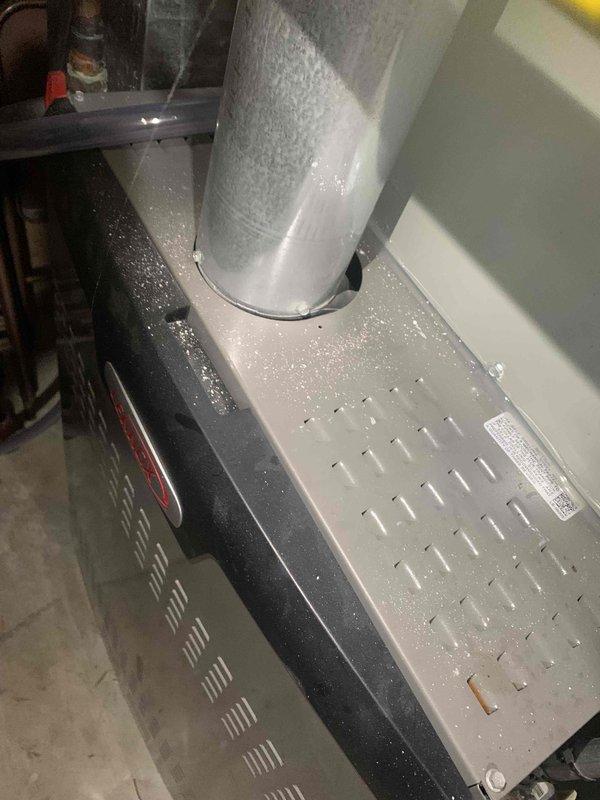 Performed a heating tune-up on one gas furnace, including inspection of the cabinet, flue vent connection, and burner/ignition components. Used an insulated probe to check internal components, and noted white mineral residue and debris on the unit's top panel, vent pipe, and cabinet edge, indicating possible condensation or moisture-related buildup that may warrant monitoring. Unit inspected and left operational.