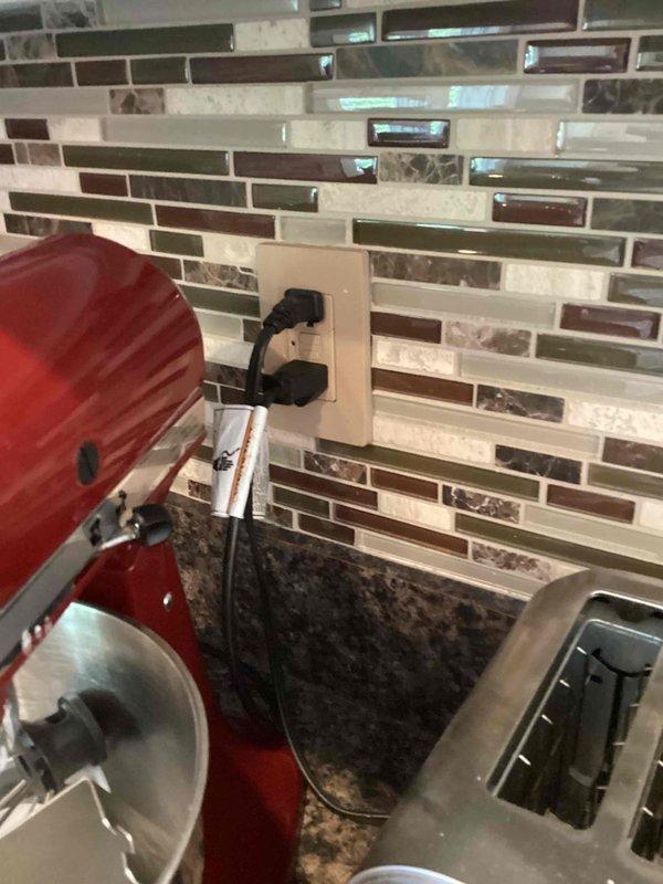 Performed an electrical inspection of the residence, including a visual examination of a double-gang switch assembly and a kitchen backsplash duplex receptacle. The two Leviton toggle switches were found mounted in a ragged, oversized drywall opening with paint and joint compound buildup on the mounting straps and no cover plate installed, while the kitchen receptacle showed no signs of damage, overheating, or abnormal conditions under normal appliance loading. The switch cutout is recommended for drywall repair and installation of a cover plate to ensure proper protection and code-compliant finish.