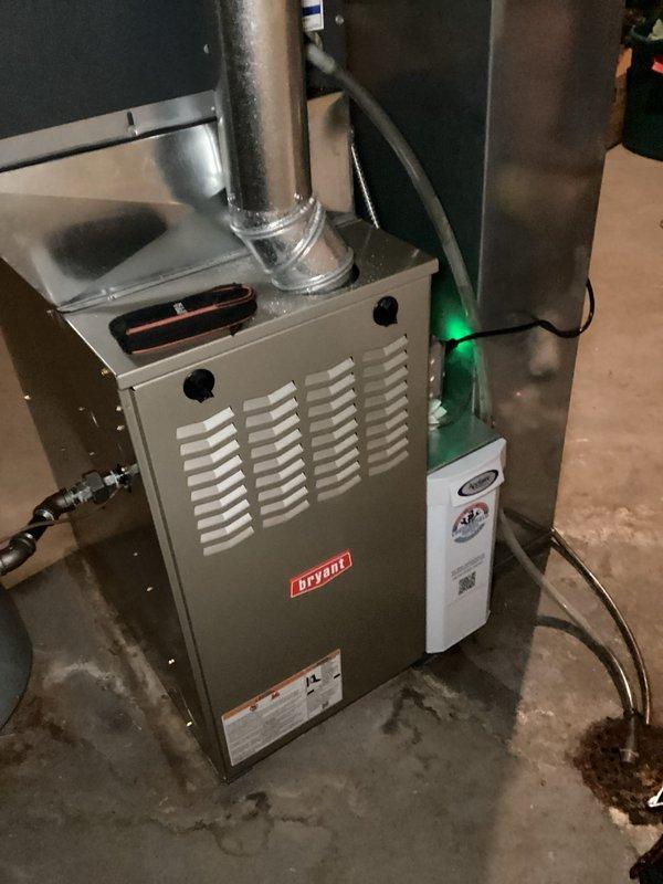 Performed seasonal heating tune-up on a 5-year-old Bryant gas furnace, inspecting the flue, gas supply connections, and humidifier assembly for proper operation. Found the return air filter heavily clogged with dust and lint, restricting airflow, and replaced it to restore proper system performance. Noted damp staining on the basement floor near the furnace base and condensate drain, which should be monitored for moisture sources.