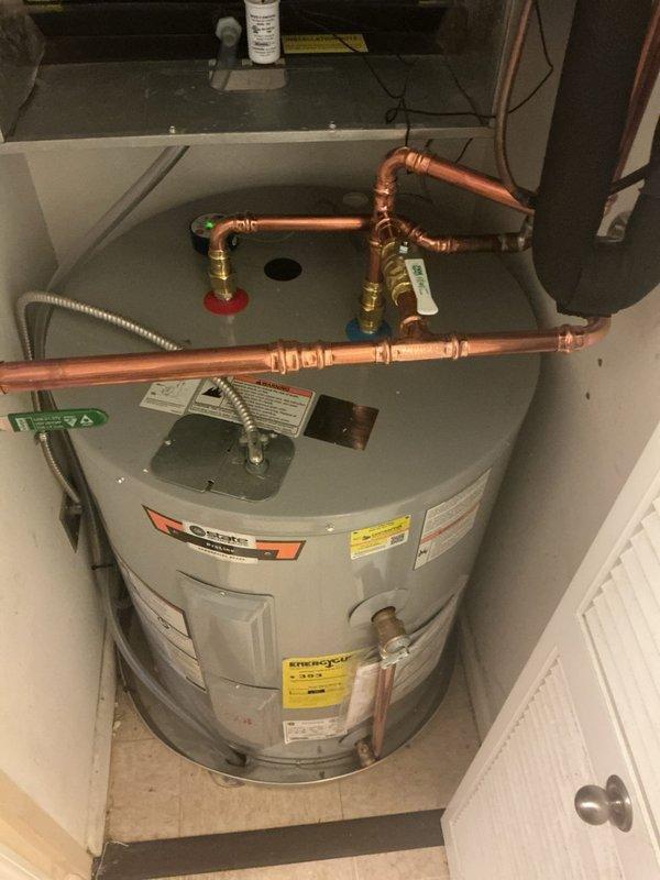 Installed a new 40-gallon short electric tank water heater in a utility closet, with new copper supply piping, brass shutoff valves, and a green-handled ball valve on the cold inlet. Connected the hot and cold lines with dielectric-protected fittings, installed a copper T&P relief discharge line, and wired the unit through flexible conduit to the electrical junction. Verified the installation is clean, leak-free, and operating properly, and applied the required permit sticker.
