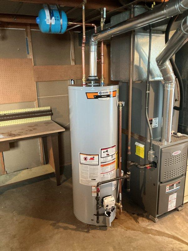 Installed a new 40-gallon tall natural gas State ProLine water heater, connecting new copper supply piping with soldered fittings, a 3/4" temperature and pressure relief valve, and a shutoff valve. Mounted an expansion tank to the supply line, reconnected the gas line, and routed the galvanized flue to the existing vent system. Verified the installation is clean and leak-free with no visible corrosion.