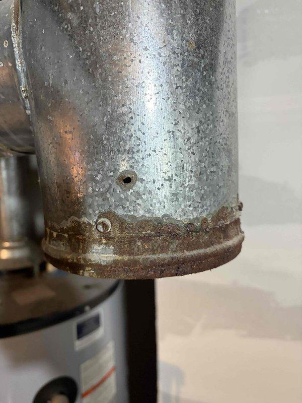 Performed a no-heat diagnostic inspection, including a visual check of the heat exchanger for cracks and an evaluation of the flame rollout switches. During the inspection, the galvanized flue/vent connector above the water heater was found to have heavy rust and corrosion along its lower edge and a pinhole perforation in the pipe wall, which presents a flue gas leakage and carbon monoxide risk. Recommend replacement of the corroded vent connector and re-inspection of the venting system for proper draft and sealing.