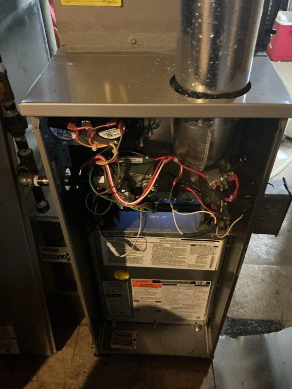 Performed a tune-up on one gas furnace, including removal of the front access panel and visual inspection of the burner compartment, flue pipe, wiring harness, and electrical components. Verified thermostat operation and noted moisture on the flue pipe and cabinet exterior along with dampness on the surrounding floor, indicating possible condensation or a leak that should be evaluated further.