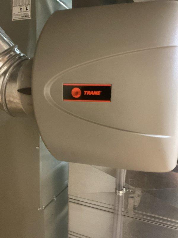 Performed annual heating tune-up on a Trane gas furnace with an attached Trane humidifier, inspecting the cabinet, flue vent, gas piping, electrical junction, and ductwork connections. System was confirmed operating properly at time of service, with no rust, frost, or equipment damage observed; a damp stained area was noted on the concrete floor near the base of the furnace and should be monitored.