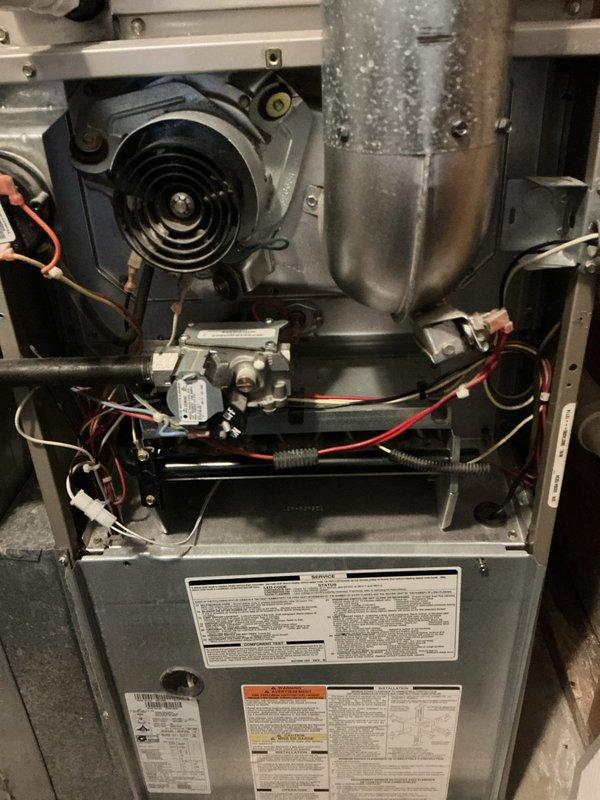 Performed a preventive heating tune-up on a 16-year-old gas furnace, inspecting the inducer motor assembly, flue piping, gas valve, burner and heat exchanger area, and control wiring with the access panel removed. Noted accumulated dust and grime on the internal components, and verified the wiring harnesses, connections, and air filter media were intact with no visible damage, rust, or other anomalies. The system was operating properly with no issues found at completion.