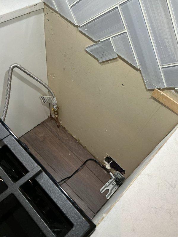Performed an on-site electrical estimate for a gas range installation and a potential new receptacle. Inspected the range area, including the flexible gas connector and shutoff valve, the exposed rear wall with rough openings near the floor, and the existing range power cord and nearby backsplash outlets. Documented existing conditions with photos to determine the scope of work and electrical requirements for the proposed outlet.