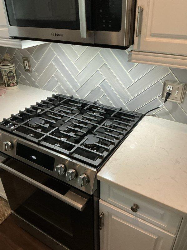 Performed an on-site electrical estimate for a gas range installation and a potential new receptacle. Inspected the range area, including the flexible gas connector and shutoff valve, the exposed rear wall with rough openings near the floor, and the existing range power cord and nearby backsplash outlets. Documented existing conditions with photos to determine the scope of work and electrical requirements for the proposed outlet.