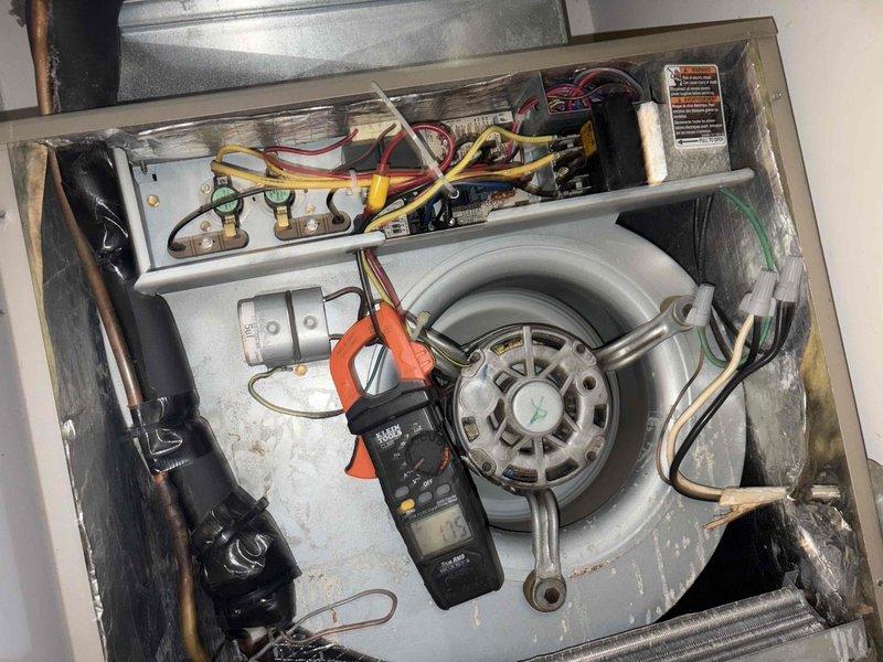 Performed a tune-up on the furnace/air handler, inspecting the blower assembly, motor, capacitor, control board, relays, and wiring connections, and verifying blower motor amperage with a clamp meter. Inspected and cleaned the cabinet interior, noting debris and staining along the interior wall, and checked the refrigerant line insulation and coil area. Replaced the dirty air filter with a new pleated filter, secured it in place, and dated it for the next maintenance interval.