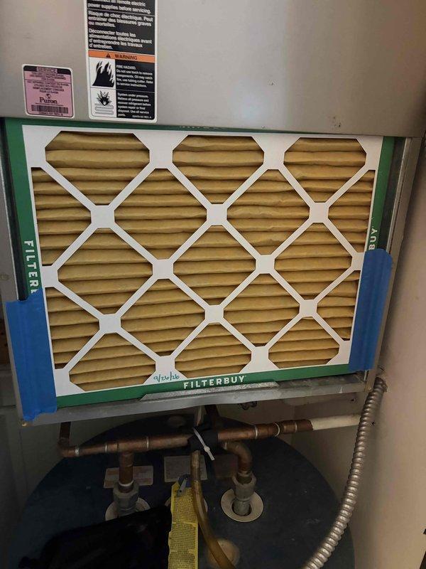 Performed a tune-up on the furnace/air handler, inspecting the blower assembly, motor, capacitor, control board, relays, and wiring connections, and verifying blower motor amperage with a clamp meter. Inspected and cleaned the cabinet interior, noting debris and staining along the interior wall, and checked the refrigerant line insulation and coil area. Replaced the dirty air filter with a new pleated filter, secured it in place, and dated it for the next maintenance interval.