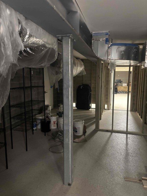 Completed HVAC system assessment of mechanical room installation. Documented existing air handler unit mounted on wall-mounted shelf system with associated ductwork and electrical connections, as well as basement-level flex duct distribution system requiring proper tensioning and securing of loosely draped sections to meet code compliance standards.
