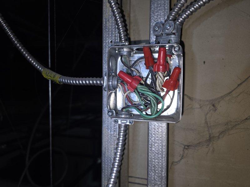 Completed electrical junction box inspection and organization in commercial space. Secured wire connections using appropriate wire nuts, verified proper conductor splicing of black, white, and green wires within metallic junction box mounted on metal stud framing. Ensured all flexible metallic conduits entering box were properly secured and connections met code requirements. All junction boxes serviced and left in compliant condition with proper covers installed.