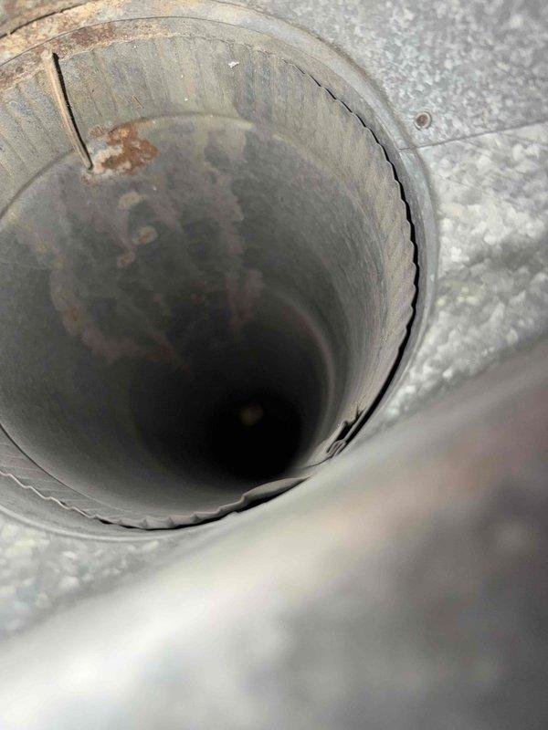 Performed comprehensive cleaning of one HVAC duct system, removing accumulated dust and debris from ventilation components. Inspected and documented areas of concern, including rust formation and structural damage (split/crack) in circular metal ductwork. System was thoroughly cleaned and photographed for documentation purposes, with special attention given to the wooden-framed rectangular return vent and metal circular duct sections.