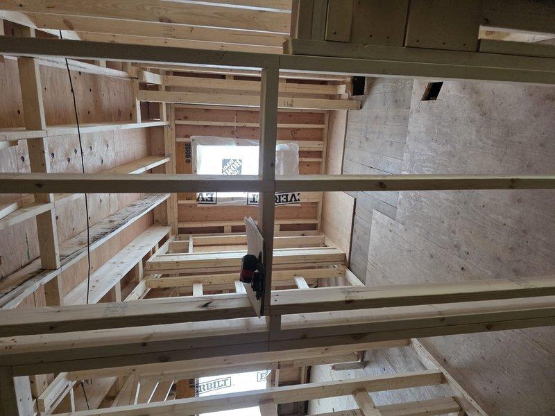 Conducted site assessment of de-roof construction to evaluate HVAC integration requirements. Inspected newly installed plywood panels within wooden framework and examined exposed interior framing structure with multiple levels of unfinished lumber studs and joists. Documented current construction phase with photographs to develop appropriate HVAC system installation plan.