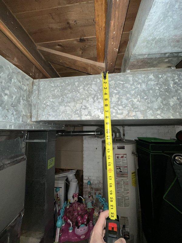Performed site assessment for relocation of existing furnace and associated ductwork. Evaluated current basement installation, taking measurements of ceiling height (approximately 22 inches clearance) and documenting existing duct configuration. Assessed structural considerations including exposed joists and available space for equipment repositioning.