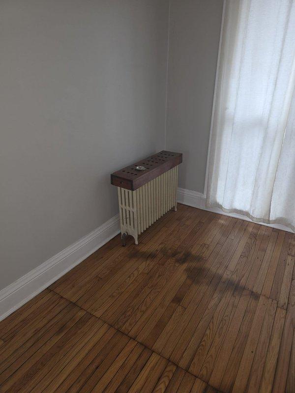 Performed estimate for replacement of vintage-style column radiator in residential setting. Current radiator (white/cream with wooden top panel) requires replacement per previous assessment. Noted existing HVAC system includes furnace installed in 2016 with connected copper piping and ventilation components.