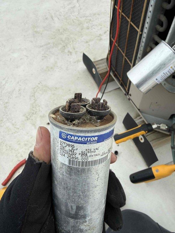 Performed diagnostic testing on commercial HVAC system and identified a severely damaged capacitor with burnt terminals and compromised housing. Successfully replaced the failed capacitor, which showed zero microfarad reading on Fieldpiece SC480 multimeter, and verified proper system operation after repair.