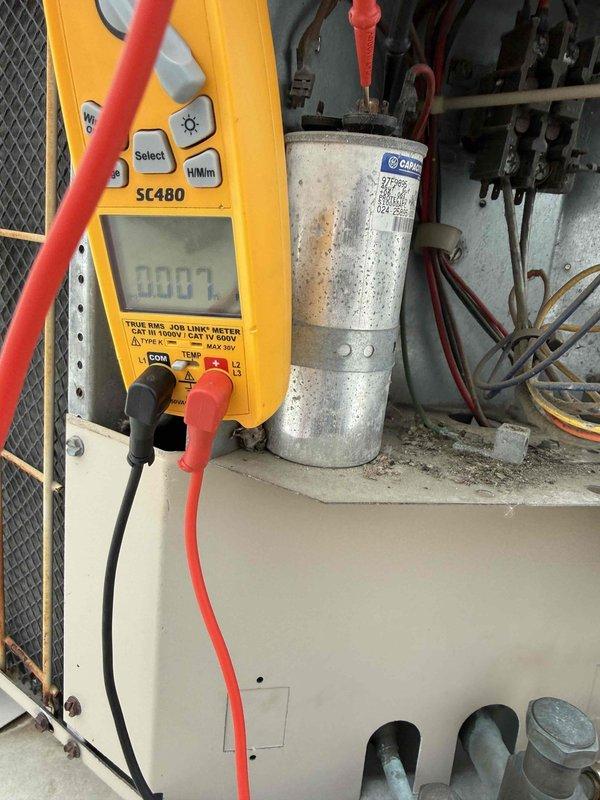 Performed diagnostic testing on commercial HVAC system and identified a severely damaged capacitor with burnt terminals and compromised housing. Successfully replaced the failed capacitor, which showed zero microfarad reading on Fieldpiece SC480 multimeter, and verified proper system operation after repair.