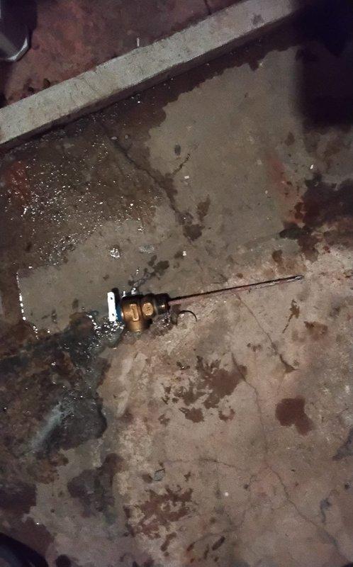 Returned to service an Indirect NTI Water Heater exhibiting a slow drip from the bottom with slight overflow into the catch pan. Diagnosed and replaced defective temperature and pressure relief valve that was causing the leakage, as evidenced by water pooling and staining on the concrete floor below the unit. System now operating properly with no signs of leakage.