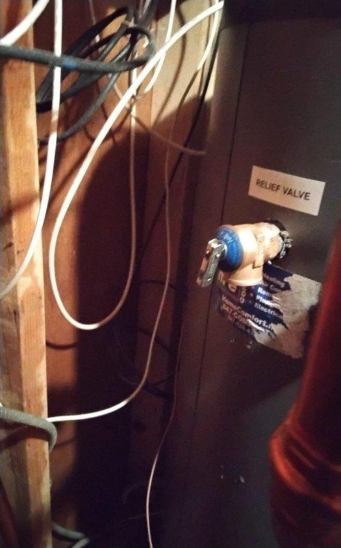 Returned to service an Indirect NTI Water Heater exhibiting a slow drip from the bottom with slight overflow into the catch pan. Diagnosed and replaced defective temperature and pressure relief valve that was causing the leakage, as evidenced by water pooling and staining on the concrete floor below the unit. System now operating properly with no signs of leakage.