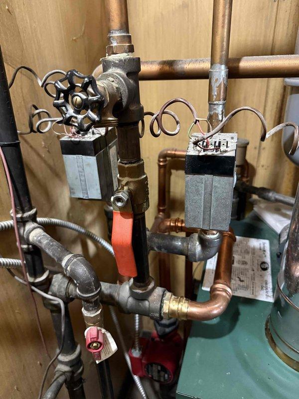 Performed annual boiler clean and check service on residential heating system. Inspected copper piping network, valves, zone control devices, and green boiler unit with exhaust venting. System shows normal aging but remains in functional operating condition with no immediate issues requiring repair.