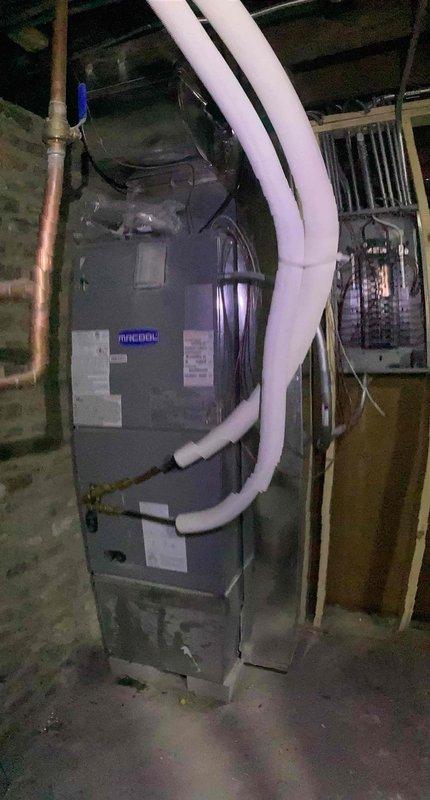 Responded to service call for Ruud heat pump system showing error code 07. Inspected HVAC installation in basement utility area, examining ductwork connections and refrigerant lines. Assessed brass pipe assembly with potential refrigerant leak at coil connection point, cleaned residue, and verified proper operation after resolving the error condition.