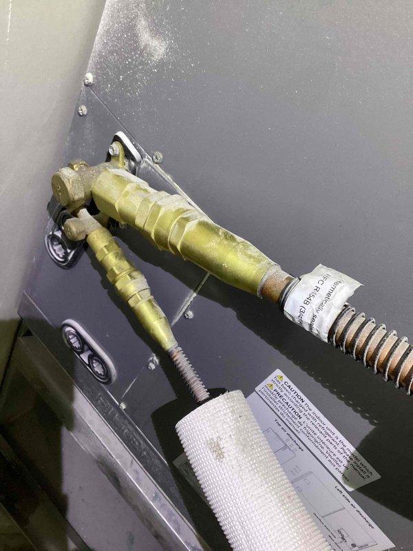 Responded to service call for Ruud heat pump system showing error code 07. Inspected HVAC installation in basement utility area, examining ductwork connections and refrigerant lines. Assessed brass pipe assembly with potential refrigerant leak at coil connection point, cleaned residue, and verified proper operation after resolving the error condition.