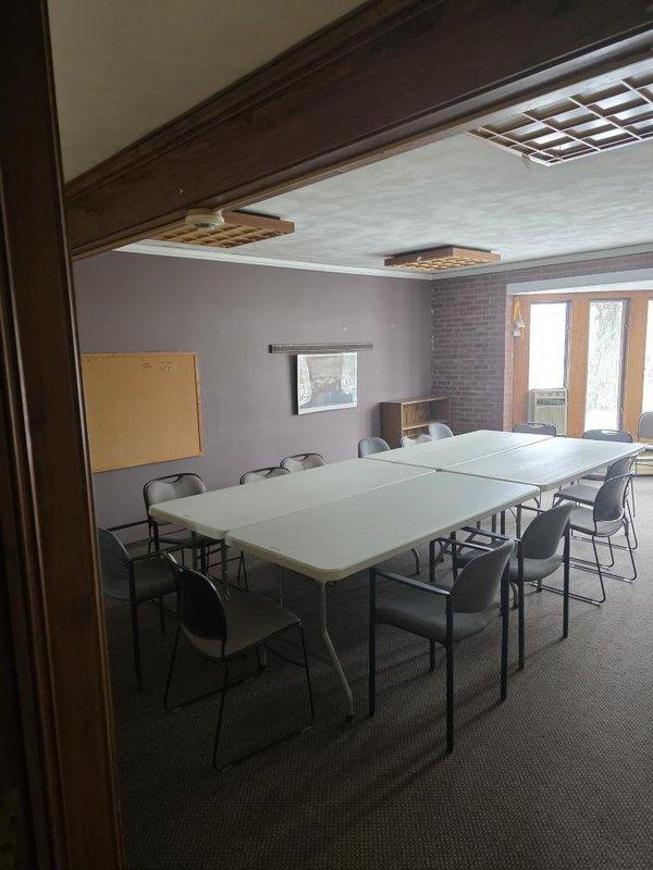 Conducted full system assessment of commercial HVAC unit located in utility room showing significant dust accumulation and requiring maintenance. Evaluation included inspection of equipment positioning against block/brick wall junction and associated ductwork. Noted conference room served by system requires adequate climate control for occupant comfort during meetings.