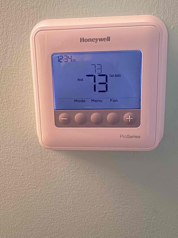 Responded to service call for reported short-circuiting issue and continuously running fan. Upon arrival, inspected Honeywell ProSeries programmable thermostat and found system operational with proper display function showing 73°F in heating mode with fan set to auto. Verified air handler installation with active 5-year parts warranty (installed 2019) and condensing unit with 10-year parts warranty. Inspected air handler unit and confirmed pleated air filter installed and accessible, with evaporator coil and condensate drain lines in satisfactory condition.