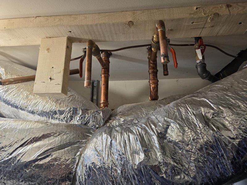 Conducted new construction site inspection of HVAC installation and plumbing rough-in. Documented copper water supply lines with shut-off valves properly secured to ceiling joists, flexible aluminum ductwork with reflective insulation installed and routed through mechanical space. All systems photographed for quality control and project records, with installations appearing ready for next phase of construction pending final connections and testing.