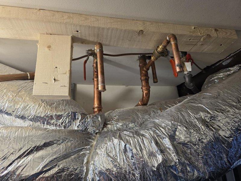 Conducted new construction site inspection of HVAC installation and plumbing rough-in. Documented copper water supply lines with shut-off valves properly secured to ceiling joists, flexible aluminum ductwork with reflective insulation installed and routed through mechanical space. All systems photographed for quality control and project records, with installations appearing ready for next phase of construction pending final connections and testing.