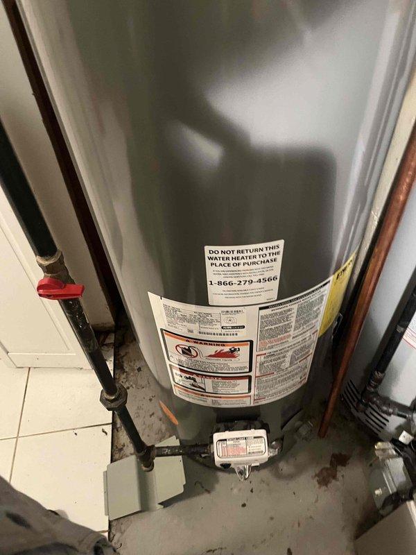Completed tanked water heater installation in residential utility area with exposed beam construction. Installed new gray cylindrical water heater with proper copper piping connections, pressure relief valve, and all required fittings to code specifications. Relocated existing water heater to front position of unit as requested, requiring additional pipe fittings and labor to properly configure dual water heater setup. Both units now operational with appropriate clearances maintained alongside existing furnace and HVAC ductwork in mechanical room.